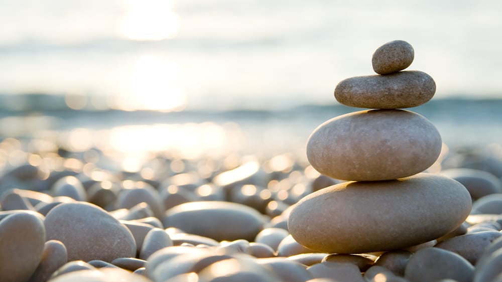 positive thinking ocean stones stacked on peaceful beach